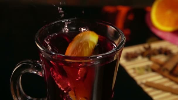 Rebanada de naranja cae en una hermosa taza de vino caliente — Vídeos de Stock