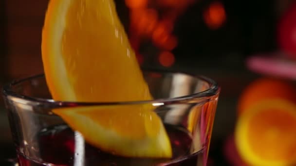 Rebanada de naranja cae en una hermosa taza de vino caliente — Vídeo de stock