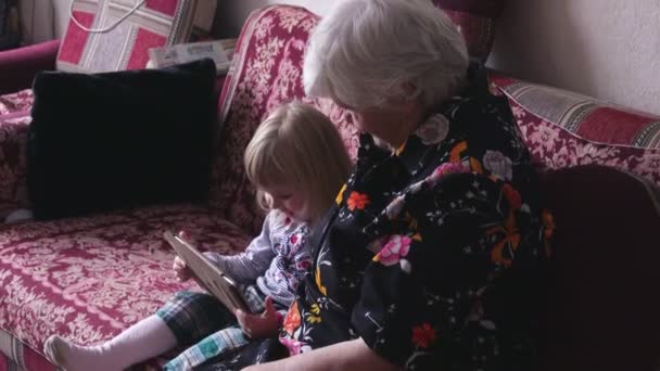 Mormor och barnbarn sitter på soffan — Stockvideo