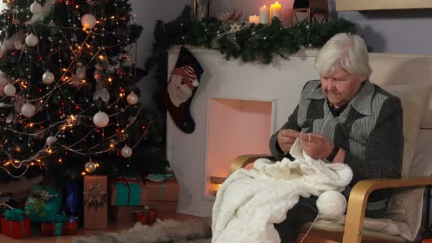 老年女子编织一条毯子，坐在椅子上 — 图库视频影像