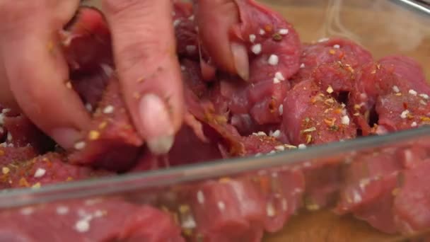 Gros plan d'une main brassant des morceaux de viande fraîche — Video