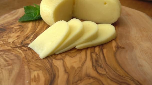 Cabeça de queijo Babybel na mesa rústica com pedaços cortados — Vídeo de Stock