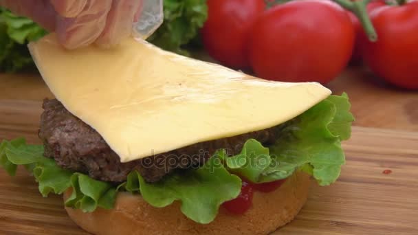 Cheddar-Käse wird auf einen Burger gelegt