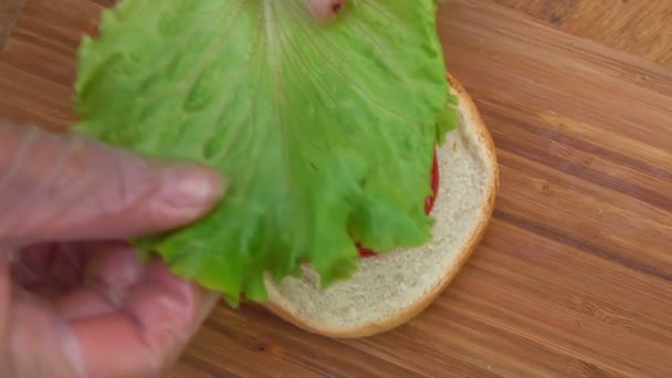 Szef kuchni stawia liść sałaty na bułce — Wideo stockowe