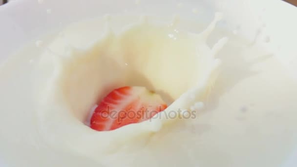 Mezza fragola che cade in una ciotola con crema — Video Stock