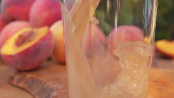 Крупный план персикового сока, налитого в стакан — стоковое видео