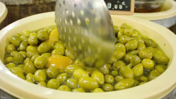 Verkoper zet groene olijven met citroen — Stockvideo