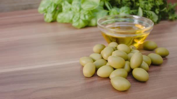 Оливки лежат рядом со стеклянной миской с оливковым маслом — стоковое видео
