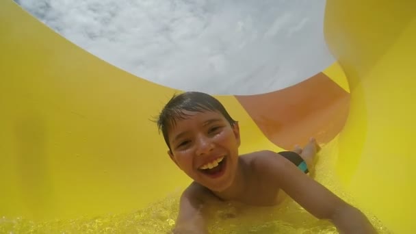 Pequeno menino engraçado rola um slide de água — Vídeo de Stock