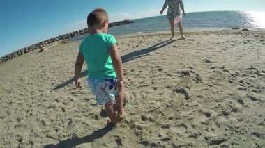 Küçük çocuk kumsalda futbol oynarken