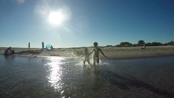 Jongens hand in hand lopen op het water — Stockvideo