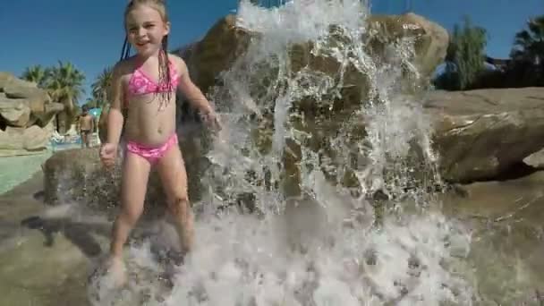 Pequena menina bonita fica sob jatos de água — Vídeo de Stock