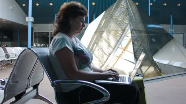 Vrouw die werkt op een laptop op de luchthaven — Stockvideo