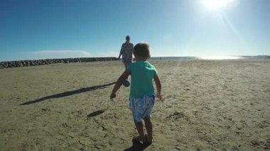 Küçük çocuk kumsalda futbol oynarken