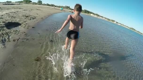 Хлопчик біжить уздовж пляжу — стокове відео