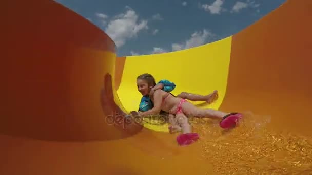 재미 있는 소년과 소녀는 노란색 워터 슬라이드를 갖춘 롤 — 비디오