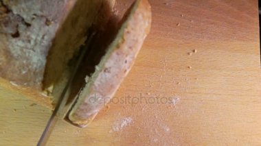 Ağır çekim bir somun tahıl ekmeği keserek bıçak