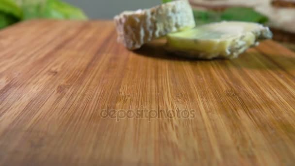 Bit av naturlig get ost Le Sainte Maure faller på en yta av trä — Stockvideo
