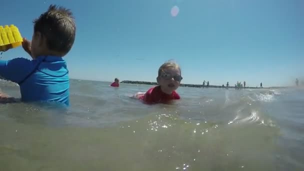 Chlapec a dívka hraje v pobřežních vlnách — Stock video