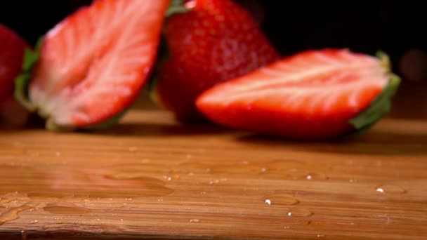 Reife Erdbeeren fallen auf ein nasses Holzbrett — Stockvideo