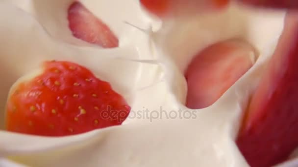 Trozos de fresas que caen en la crema batida — Vídeo de stock