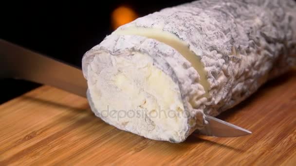 Queso de cabra con molde gris se corta con un cuchillo en una tabla de madera — Vídeo de stock