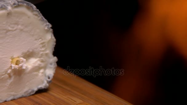 Козий сыр на фоне горящего камина — стоковое видео