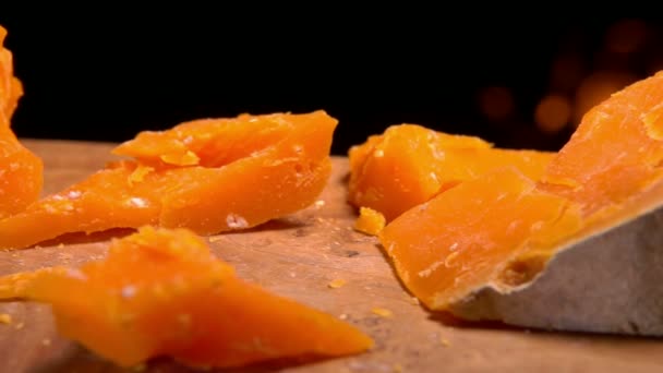 Pedazo de queso Mimolett cae sobre una tabla de madera — Vídeo de stock