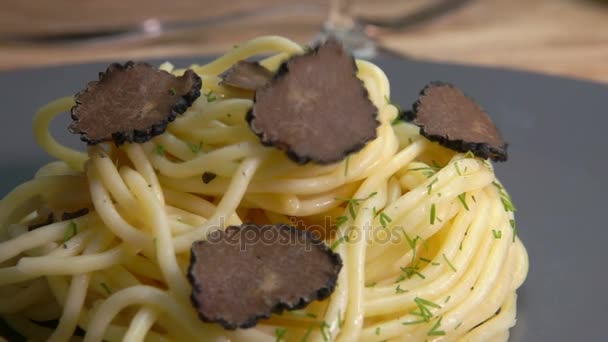 Segmenten van de zwarte truffel vallen op spaghetti — Stockvideo