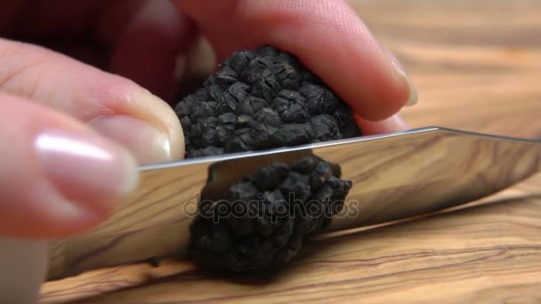 Zwarte truffel snij met mes in plakjes op een houten bord — Stockvideo