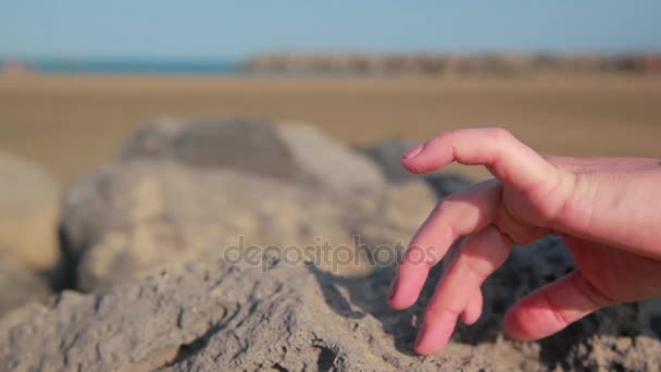 По песку движется женская рука с браслетами — стоковое видео