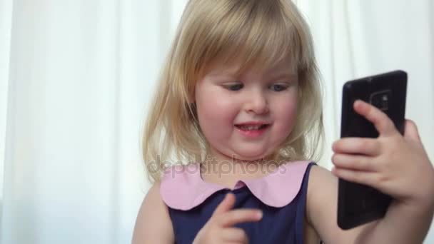 Indah biru bermata gadis membalik melalui foto di telepon — Stok Video