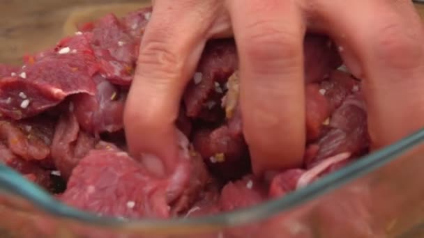 Close-up van een hand roeren stukken van vers vlees — Stockvideo
