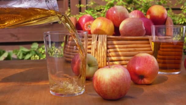 Sok jabłkowy i kosz dojrzałe jabłka na drewnianym stole — Wideo stockowe