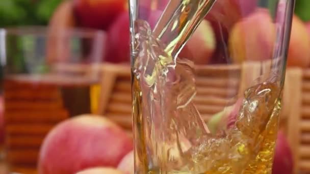 Apfelsaft Apfelsaft wird in ein Glas gegossen und Korb mit Äpfeln — Stockvideo