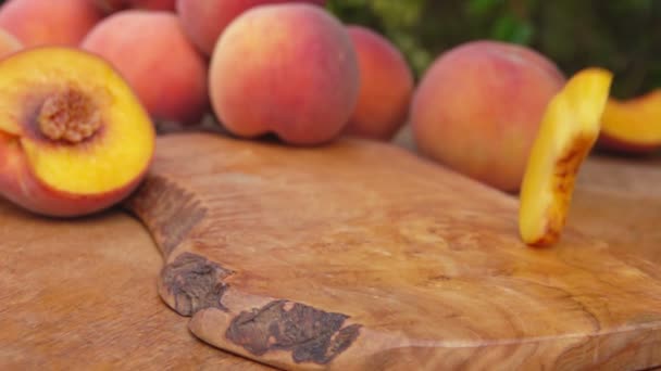 Кусочки персиков падают на деревянный стол — стоковое видео