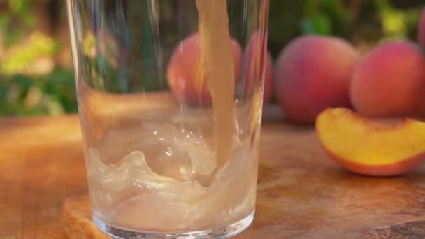 Perziksap wordt in een glas gegoten — Stockvideo