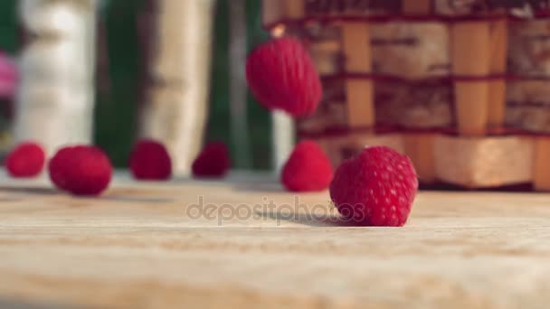 Raspberrys падає на стіл поруч із плетеними кошику — стокове відео