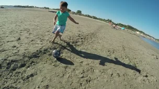 Liten pojke som spelar fotboll på stranden — Stockvideo