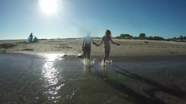 Kinderen die hand in hand lopen op het water — Stockvideo