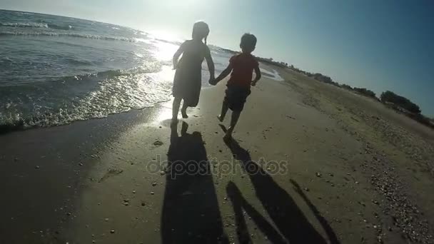 Fröhliche Mädchen und Jungen, die barfuß im Sand laufen — Stockvideo