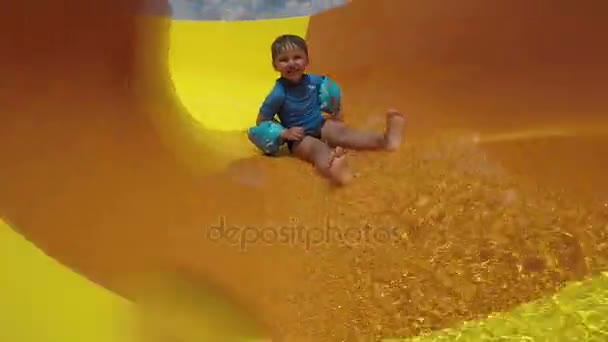 Забавный мальчик с желтыми водными горками — стоковое видео