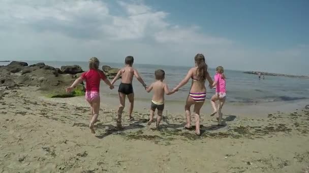 Kinderen lopen hand in hand door het zand — Stockvideo