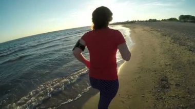 Kız plaj boyunca gün batımında çalışır.