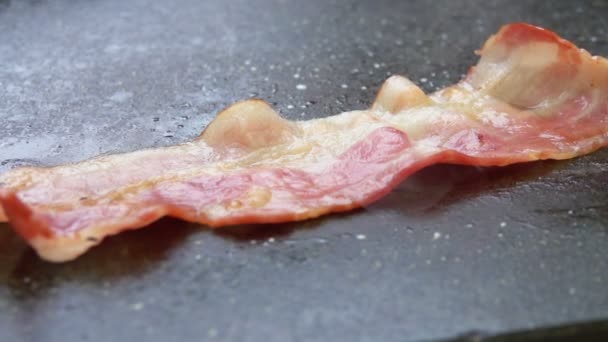 Närbild av en skiva bacon lägger på grillen — Stockvideo