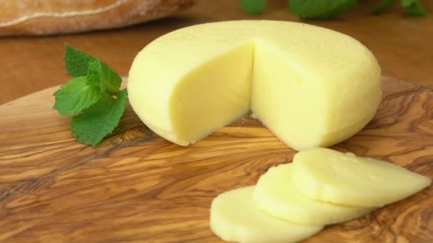 Cabeza de queso Babybel en la mesa rústica con trozos en rodajas — Vídeos de Stock