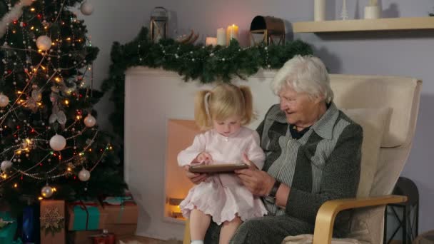 Девушка со своей бабушкой смотрит на фотографии планшета — стоковое видео