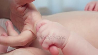 Gri arka plan üzerinde bir yetişkin elini tutarak bebek