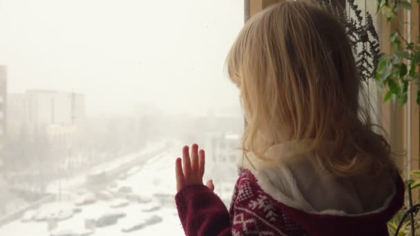 Mooie blauwogige meisje kijkt door het raam — Stockvideo