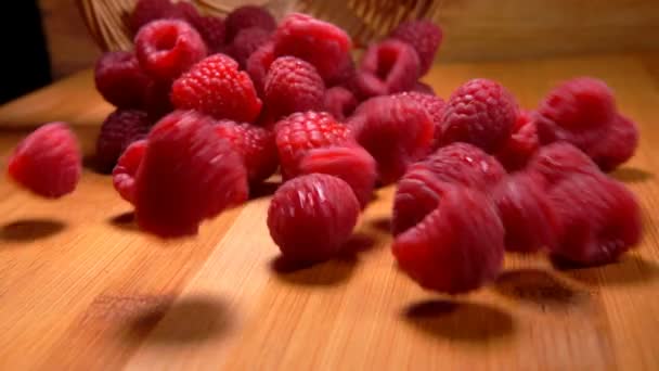 Raspberrys падає на стіл поруч із плетеними кошику — стокове відео